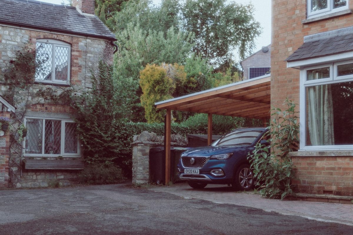 Carport en bois adossé à une maison abritant une voiture