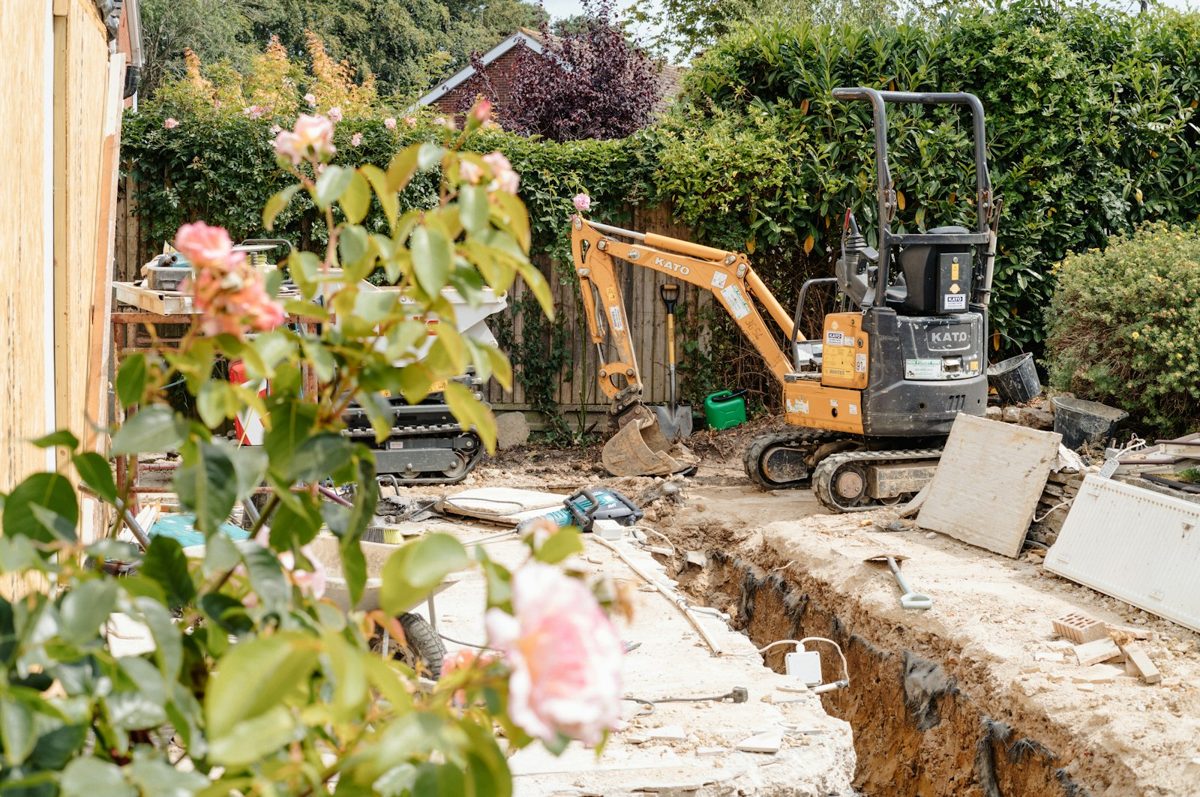 Mini-pelle creusant une tranchée de raccordement dans un jardin