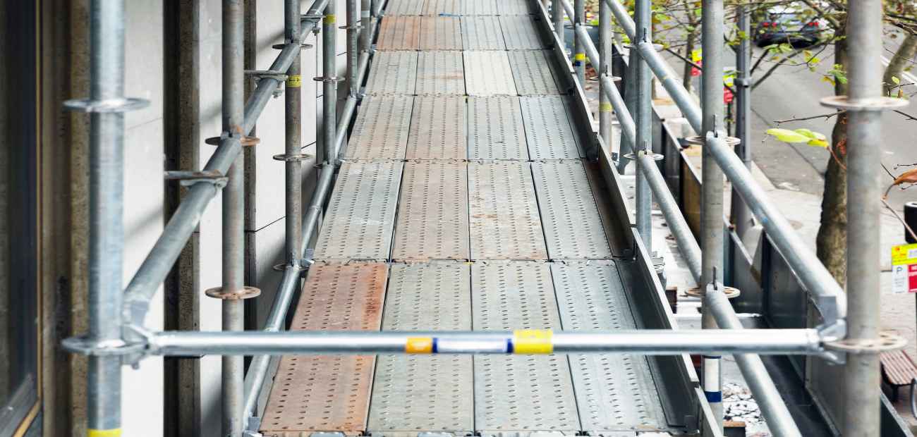 Plancher d'échafaudage composé de plateaux métalliques le long d'une façade